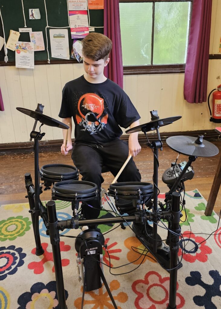 Harvey drumming on Musical Mates Drum Kit.